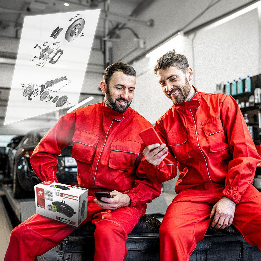 Ferodo technical drawings Two automotive mechanics in a workshop examining detailed Ferodo technical drawings accessed by scanning a Ferodo QR code on the product packaging